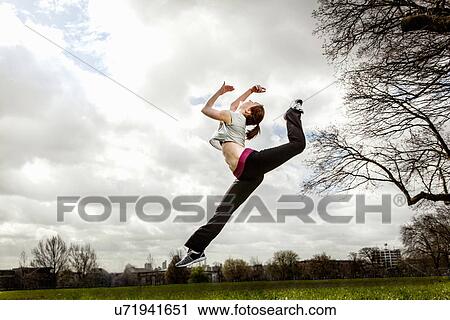 Woman jumping in mid air with bent leg View Large Photo Image Stock Image - Woman jumping in mid air with bent leg. Fotosearch