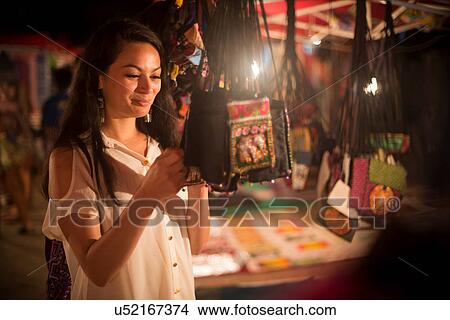 Picture - Woman looking at handbags in night market, Luang Prabang, Laos. Fotosearch