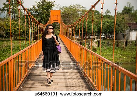 Stock Image - Woman on bridge over river, Vang Vieng, Laos. Fotosearch