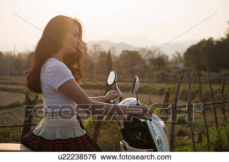 Stock Photograph - Woman on moped in rural scene. Fotosearch