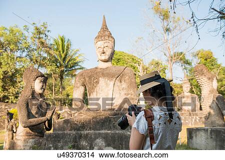 Woman photographing statue, Xieng Khu, Vientiane, Laos View Large Photo Image Picture - Woman photographing statue, Xieng Khu, Vientiane, Laos. Fotosearch