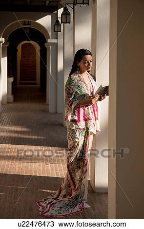 Stock Image - Woman reading by columns in hotel. Fotosearch