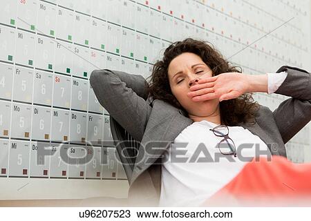 Woman sitting in office chair in front of large wall calendar View Large Photo Image Stock Image - Woman sitting in office chair in front of large wall calendar. Fotosearch