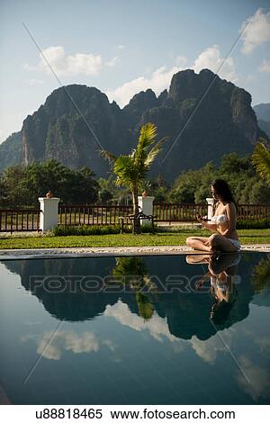 Woman sitting on poolside, Vang Vieng, Laos View Large Photo Image Stock Photography - Woman sitting on poolside, Vang Vieng, Laos. Fotosearch