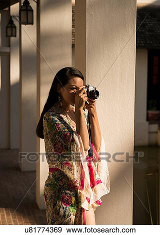 Stock Photo - Woman taking photograph by columns in hotel. Fotosearch