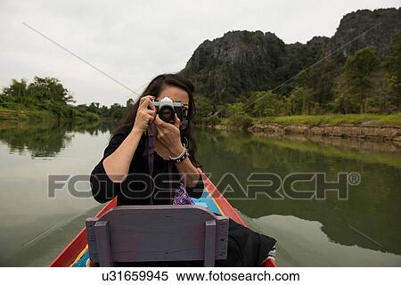 Woman taking photograph on boat on Nam Song River, Vang Vieng, Laos View Large Photo Image Stock Photography - Woman taking photograph on boat on Nam Song River, Vang Vieng, Laos. Fotosearch