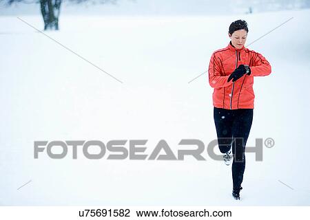 Stock Image - Woman timing her snow running. Fotosearch