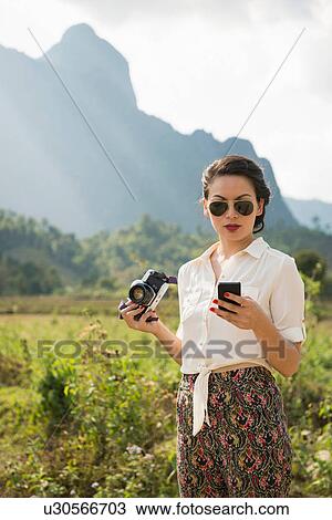 Stock Image - Woman using smartphone, Vang Vieng, Laos. Fotosearch