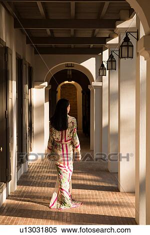 Woman walking past columns in hotel View Large Photo Image Stock Photography - Woman walking past columns in hotel. Fotosearch