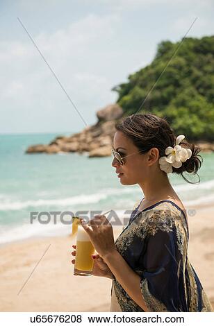 Stock Photo - Woman with drink on beach, Banyon Tree Resort, Ko Samui, Thailand. Fotosearch