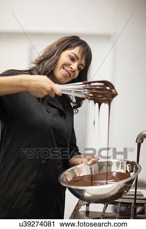 Stock Image - Woman with mixing bowl and melted chocolate. Fotosearch