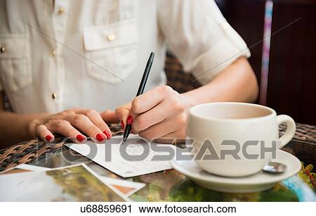 Stock Image - Woman writing postcard in cafe. Fotosearch