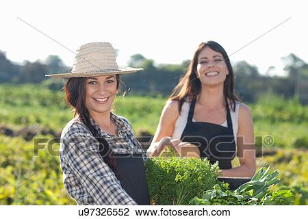 Stock Image - Women with vegetables grown at farm. Fotosearch