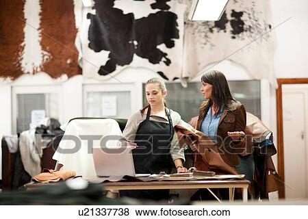 Stock Photo - Worker and customer in leather workshop. Fotosearch