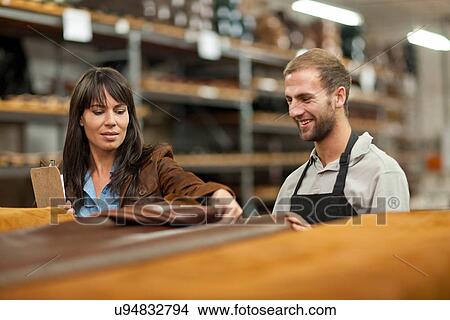 Picture - Worker and manager looking at roll of leather. Fotosearch