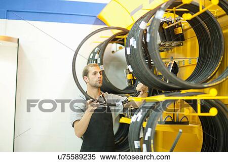 Stock Photography - Worker in bicycle shop, choosing tyre. Fotosearch