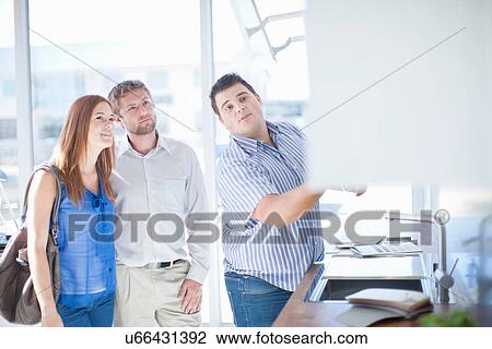 Stock Image - Young couple and salesman in kitchen showroom. Fotosearch