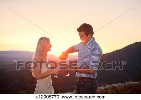 Young couple having champagne outdoors at sunset View Large Photo Image Stock Image - Young couple having champagne outdoors at sunset. Fotosearch