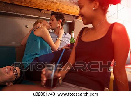 Young couple kissing, friends sitting nearby View Large Photo Image Stock Image - Young couple kissing, friends sitting nearby. Fotosearch