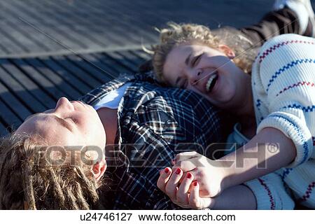 Young couple lying down, laughing View Large Photo Image Stock Photo - Young couple lying down, laughing. Fotosearch