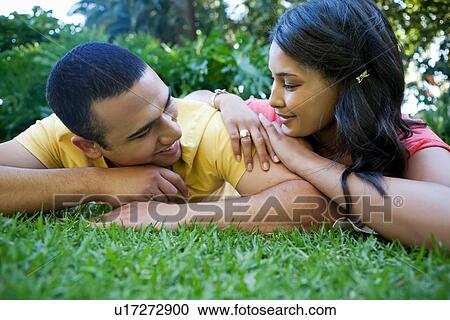 Young couple lying on grass View Large Photo Image Stock Image - Young couple lying on grass. Fotosearch