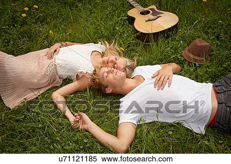 Young couple lying on grass with eyes closed View Large Photo Image Stock Photography - Young couple lying on grass with eyes closed. Fotosearch