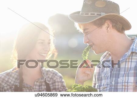 Stock Photo - Young couple trying vegetables on farm. Fotosearch