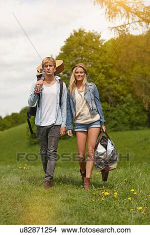 Picture - Young couple walking through field with guitar. Fotosearch
