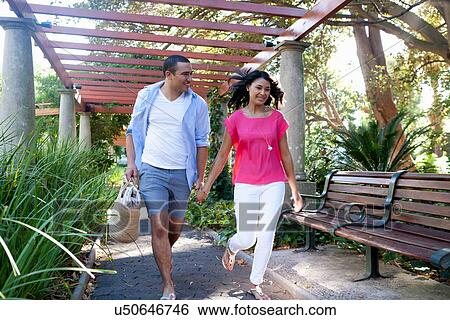 Stock Photograph - Young couple walking under canopy in garden. Fotosearch
