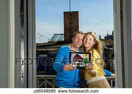 Stock Photo - Young couple with drawing of house on rooftop. Fotosearch