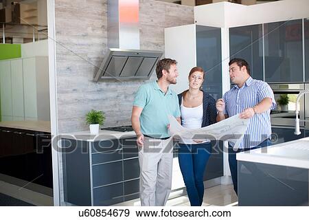 Young couple with salesman in kitchen showroom View Large Photo Image Stock Photo - Young couple with salesman in kitchen showroom. Fotosearch