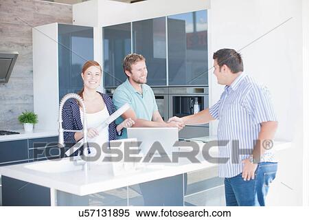 Stock Photography - Young couple with salesman in kitchen showroom. Fotosearch