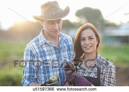 Stock Photograph - Young farm workers with aubergines grown on farm. Fotosearch
