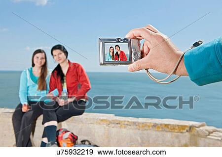 Young female friends having their photograph taken at coast View Large Photo Image Stock Photo - Young female friends having their photograph taken at coast. Fotosearch