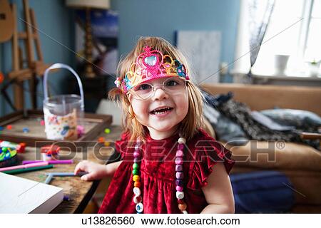 Stock Image - Young girl wearing tiara and necklace, smiling. Fotosearch