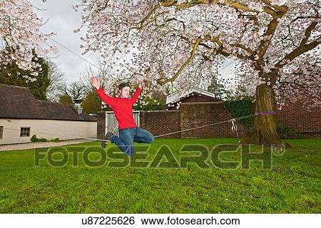 Young man balancing on a slackline View Large Photo Image Stock Photograph - Young man balancing on a slackline. Fotosearch