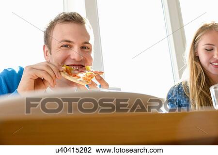 Young man eating pizza View Large Photo Image Stock Image - Young man eating pizza. Fotosearch