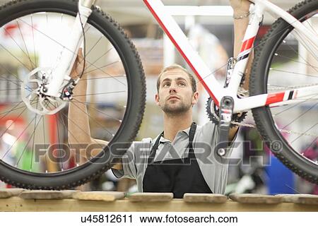 Young man holding bicycle in repair shop View Large Photo Image Stock Image - Young man holding bicycle in repair shop. Fotosearch