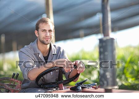 Young man on vehicle in plant nursery View Large Photo Image Stock Photo - Young man on vehicle in plant nursery. Fotosearch