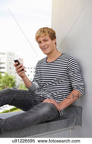 Young man sitting on apartment balcony View Large Photo Image Stock Photography - Young man sitting on apartment balcony. Fotosearch