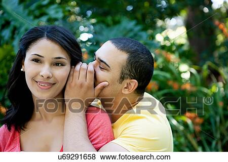 Stock Photo - Young man whispering in woman's ear. Fotosearch