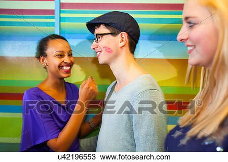 Young man with lipstick mark on cheek, women laughing View Large Photo Image Stock Image - Young man with lipstick mark on cheek, women laughing. Fotosearch