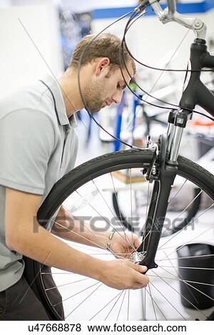 Stock Photo - Young man working on bicycle. Fotosearch