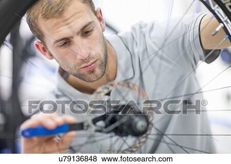 Stock Photo - Young man working on bicycle. Fotosearch