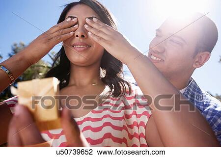 Young woman covering eyes with hands, man holding ring box View Large Photo Image Stock Image - Young woman covering eyes with hands, man holding ring box. Fotosearch
