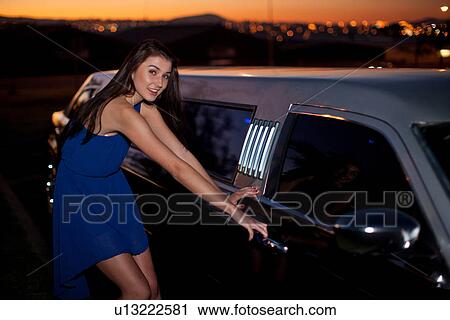 Stock Image - Young woman getting into limousine. Fotosearch
