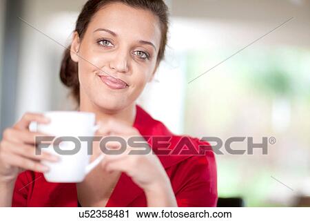 Stock Image - Young woman holding coffee cup. Fotosearch