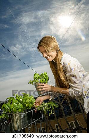 Stock Photo - Young woman holding pot plant. Fotosearch