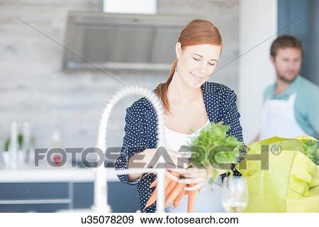 Young woman in kitchen, preparing carrots View Large Photo Image Stock Photo - Young woman in kitchen, preparing carrots. Fotosearch