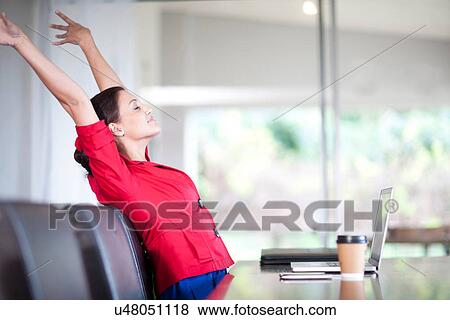 Young woman in office stretching View Large Photo Image Stock Photo - Young woman in office stretching. Fotosearch